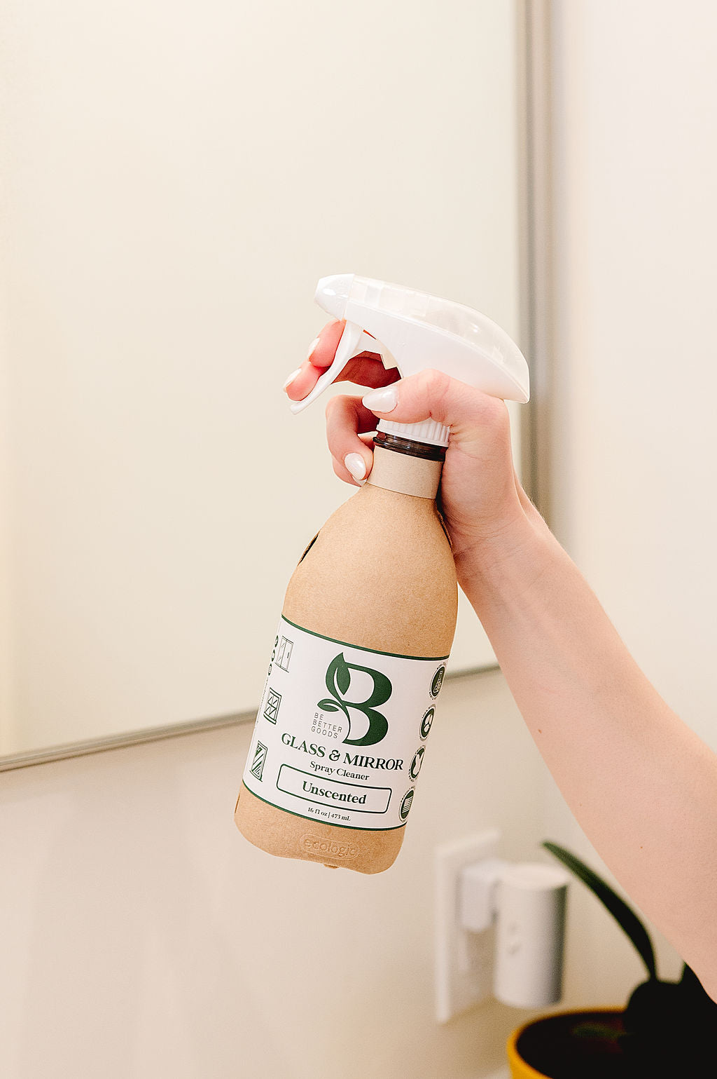 Plant-based glass cleaner in responsible packaging spraying a bathroom mirror.